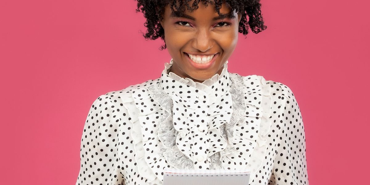 A person looking confident and accomplished, holding a writing workbook or notebook.