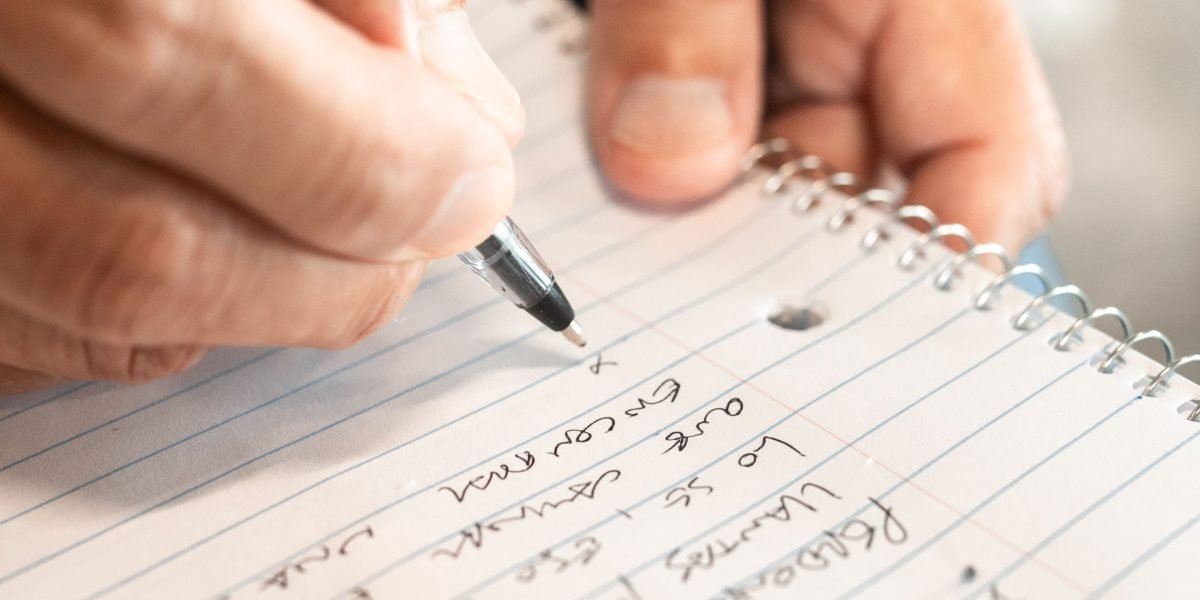A person actively writing or filling out exercises directly in a physical workbook.