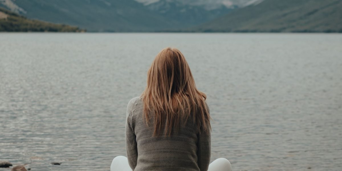 A person absorbed in thought within a natural environment, contemplating identity and surroundings.