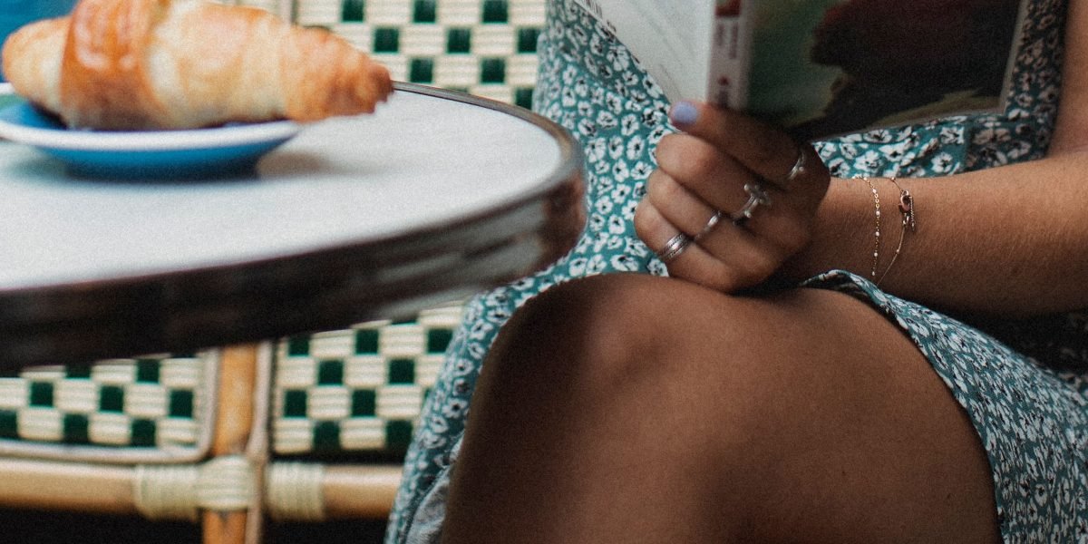 A person engrossed in a physical book within a cafe setting, symbolizing deep engagement and quiet reflection away from digital distractions.