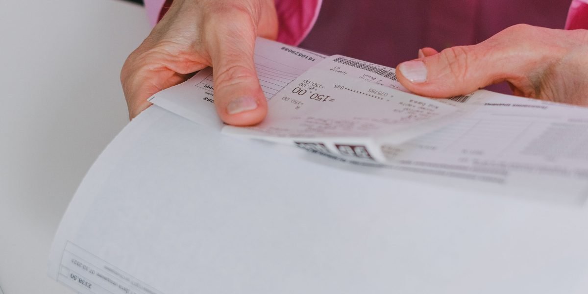 A person thoughtfully organizes financial documents, symbolizing smart budgeting and finding affordable ways to enjoy reading.