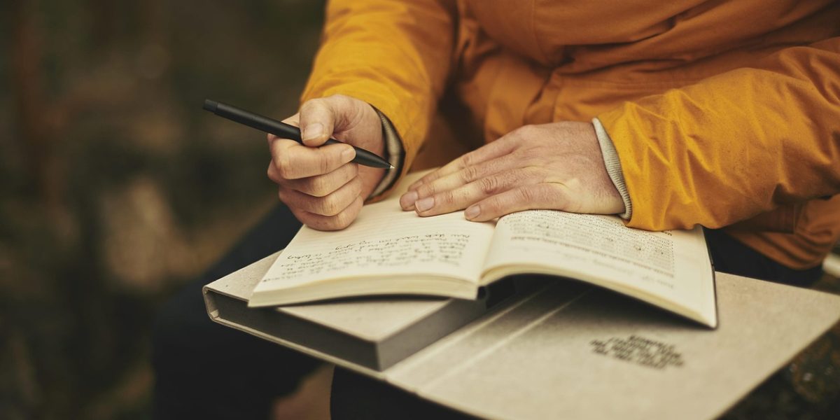 A person thoughtfully writing in a journal, reflecting on experiences or readings.