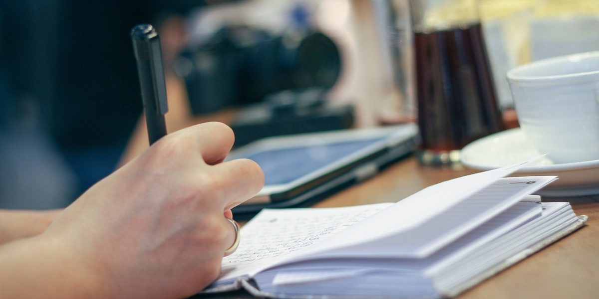 A person reflecting on their reading, actively taking notes to track character development and personal insights.
