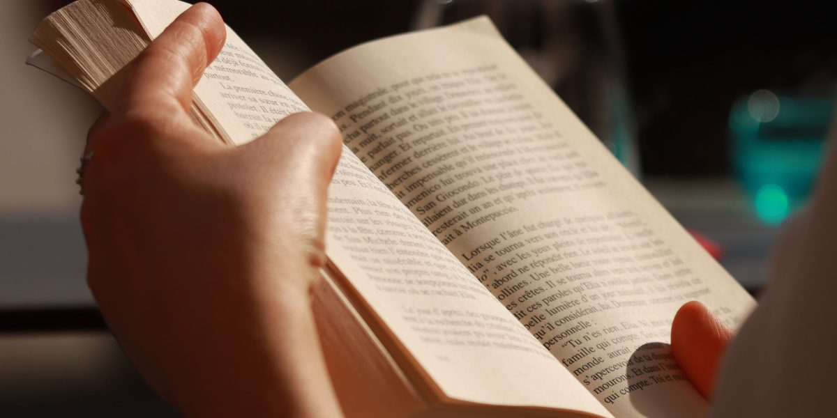 A person finds joy and relaxation while engrossed in a good sci-fi story book, embracing the pleasure of reading.