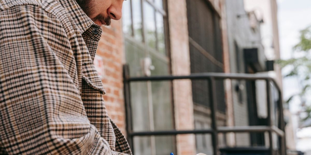 A person thoughtfully writing in a journal, connecting with ideas from a book, fostering deeper understanding.