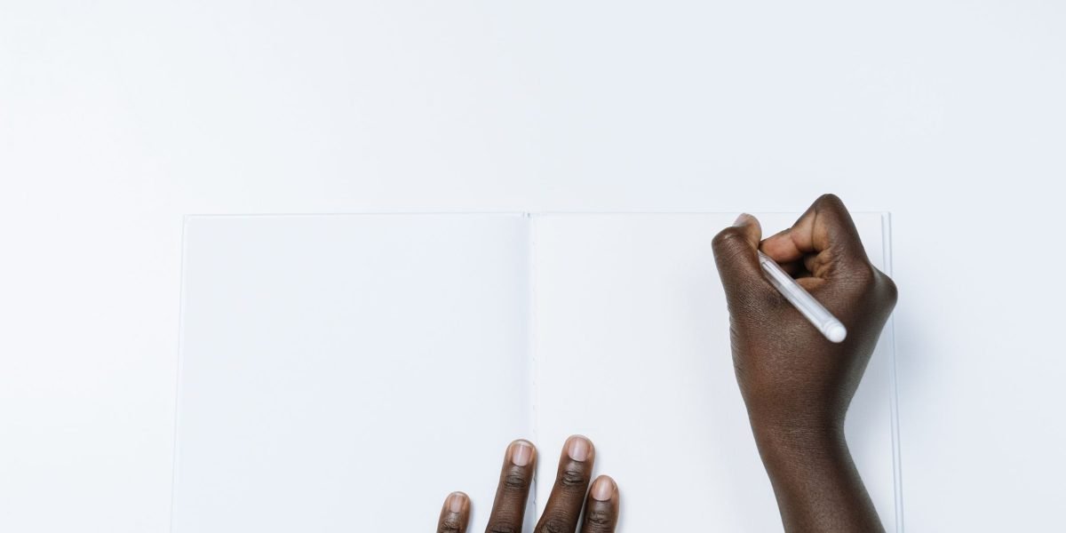 A person diligently writing in a journal, connecting thoughts from a book to their personal reflections.